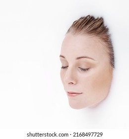 Totally Immersive Beauty. Studio Shot Of An Attractive Womans Face Emerging From A White Liquid.