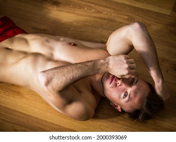 Totally naked muscular young man laying on floor