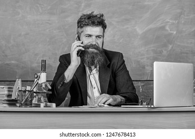 In Touch With School. School Principal Or Teacher Calling Parents To Report About Exam Results. School Teacher Cares About Communication With Parents. Man With Beard Talk Phone Classroom Background.