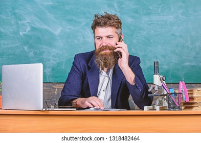 In Touch With School. School Principal Or Teacher Calling Parents To Report About Exam Results. School Teacher Cares About Communication With Parents. Man With Beard Talk Phone Classroom Background.