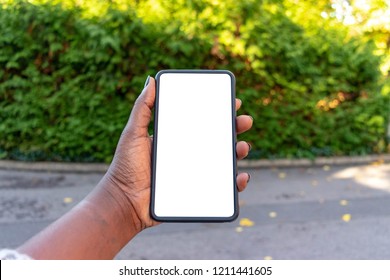 Touch Screen Mobile Phone, In African Woman's Hand. Black Female Holding Smart Phone On Green Outdoor Background With Blank Copy Space Screen For Your Text Message Or Information Content