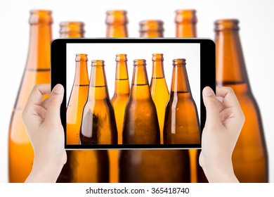 Touch screen tablet in hand a photography the beer bottles.