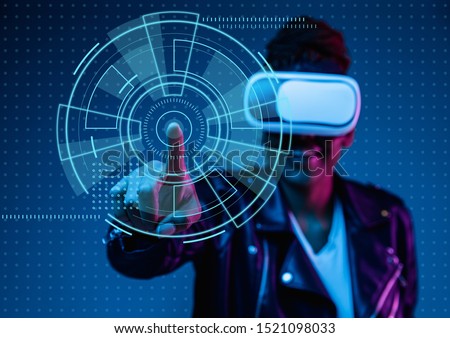 Touch of virtual reality. Young african-american woman's playing in VR-glasses in neon light on blue background. Concept of human emotions, facial expression, modern gadgets and technologies.