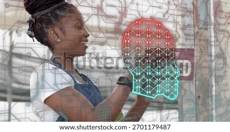 Touching clear panel tech in overalls using neon brain circuit graphics in workshop, copy space. Denim, maker, lab, smartwatch, futuristic, glass, woman