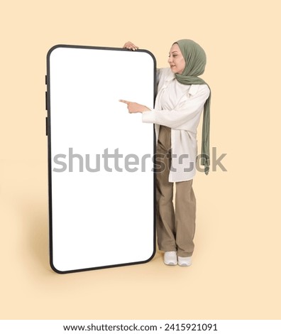 Touching display panel, full length body view young muslim woman wear hijab touching display panel. Using big huge smartphone mobile phone mock up. White blank screen. Advertising design concept.