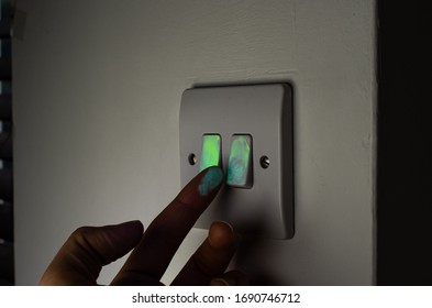 Touching Light Switch Glowing Under UV Light Visualisation Exposing Germs And Viruses Spreading.