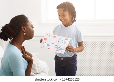 Touching Moment. African kid showing greeting card with I Love You, Mother text to her mom