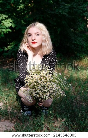 touching portrait of a charming blonde girl with bouquet of white wildflowers. female with flowers.