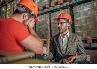 Tough Conversation. Manager Having A Tough Conversation With The Warehouse Worker And Looking Angry