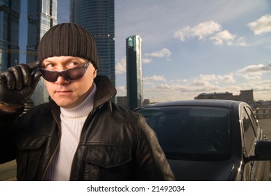 Tough Guy In Leather Jacket Near His Car And Skyscrapers At Background