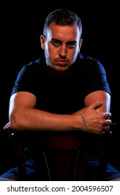 Tough Guy Sitting On A Chair. Low Key Studio Portrait.