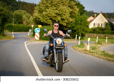 Tough Guy With Sparrow Beard, Undercut And Blue Jeans In Motion On The Road On A Chopper Bike