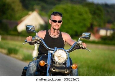 Tough Guy With Sparrow Beard, Undercut And Blue Jeans In Motion On The Road On A Chopper Bike