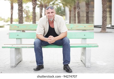 Tough Looking Man Sitting On A Bench