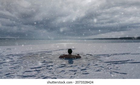 A tough man sitting an ice hole while having an ice bath in a frozen lake
