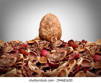 Tough nut to crack business concept as a solid hard closed walnut on top of a mountain of broken nut shells as a metaphor for difficulty solving a problem or difficult person symbol.