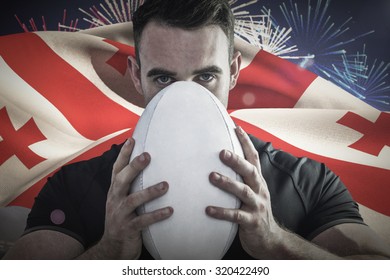 Tough rugby player holding ball against fireworks exploding over football stadium - Powered by Shutterstock