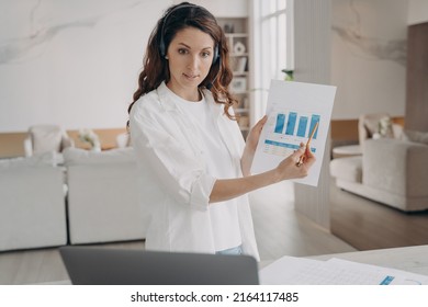 Tough spanish woman has corporate internet session on laptop. Young pretty leader shows charts and pointing to the data. Businesswoman is brainstorming online from home. Remote business on quarantine.