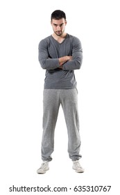 Tough young serious athletic sporty man staring at camera with crossed arms. Full body length portrait isolated on white studio background. 
