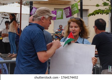 Toulouse, France - June 25, 2020 - An anti Zionist activist with a flag of Palestine and a sign claiming "Free speech for BDS", talks with a man at an election meeting of ecologist Antoine Maurice