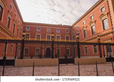 Toulouse, France - Sept. 2019 -  Front facade and wrought-iron gate of the Court of Appels, a part of the Palace of Justice, built of red brick ; the portals are decorated with golden spearheads