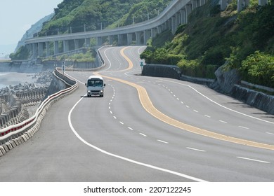 Tour Bus Driving On Curved Coast Highway Beside The Elevated Railway