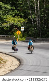 Touring Bicycles Riding In Vancouver Island, Canada. Woman And Man Cycling On A Mountain Road Taking A Curve. Street View, Travel Photo, Selective Focus-August 9,2021.