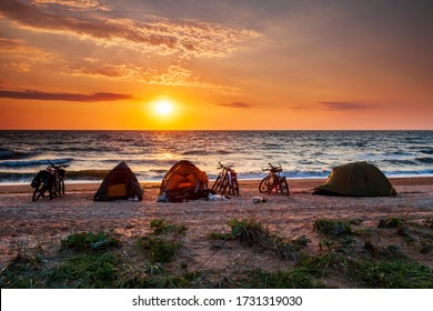 Touring bikes and tents during sunrise on the beach. Camping on a sandy beach. Arabat spit, Azov Sea, Ukraine.