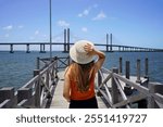 Tourism in Aracaju, Brazil. Back view of young woman on pier in Aracaju with Ponte Joao Alves bridge on the background, Brazil.