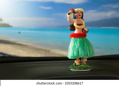 Tourism Concept. Hula Dancer Doll On Dashboard Car. The Car Is Parking In Front Of The Ocean. The Hula Dance Is One Of Hawaii's Oldest Traditions.