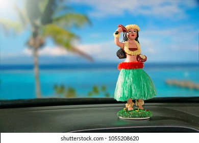 Tourism Concept. Hula Dancer Doll On Dashboard Car. The Car Is Parking In Front Of The Ocean. The Hula Dance Is One Of Hawaii's Oldest Traditions.
