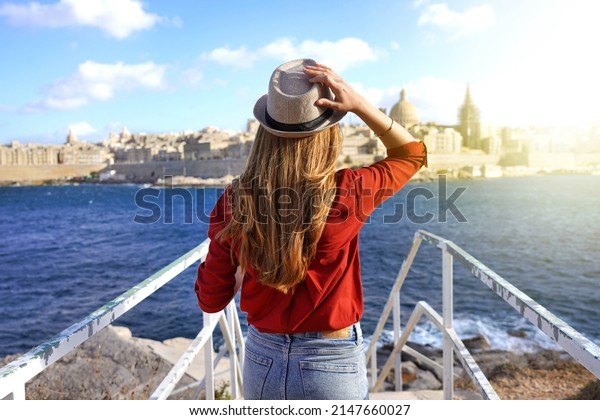 Tourism in Europe. Back view of traveler\
girl walking on stairs enjoying view of Valletta city, Malta. Young\
female tourist visiting southern\
Europe.