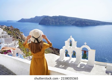 Tourism in Europe. Back view of young woman looking stunning landscape in the picturesque village of Oia, Santorini Island, Greece.