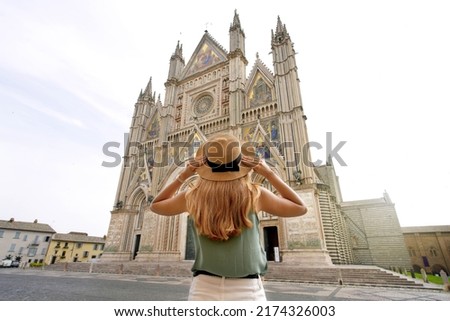 Tourism in Italy. Young woman enjoying view the well reserved Cathedral of Orvieto, Umbria, Italy.