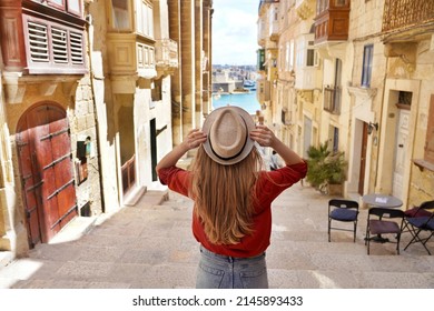 Tourism In Malta. Back View Of Tourist Girl Holding Hat Descends Stairs In The Old Town Of Valletta, UNESCO World Heritage, Malta.