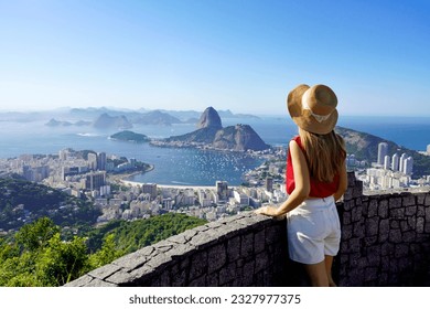 Tourism in Rio de Janeiro. Back view of traveler girl enjoying sight of famous Guanabara Bay with Sugarloaf Mountain in Rio de Janeiro, UNESCO World Heritage, Brazil.