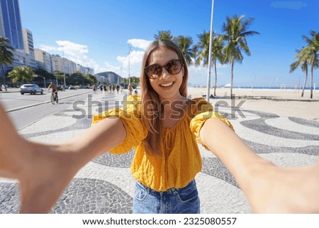 Tourism in Rio de Janeiro. Beautiful smiling girl takes self portrait on Copacabana beach promenade, Rio de Janeiro, Brazil.