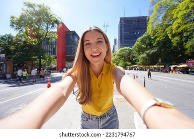 Tourism in Sao Paulo. Beautiful smiling girl takes self portrait on Paulista Avenue, Sao Paulo, Brazil. - Shutterstock ID 2231794767