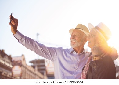 Tourism And Technology. Traveling Senior Couple Taking Selfie Together Against Sightseeing Background.