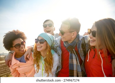 tourism, travel, people, leisure and teenage concept - group of happy friends in sunglasses hugging and laughing on city street - Shutterstock ID 274967174