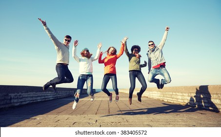 tourism, travel, people, leisure and teenage concept - group of happy friends in sunglasses hugging and laughing on city street - Powered by Shutterstock