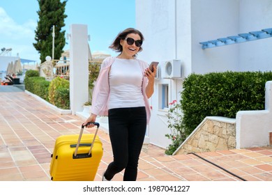 Tourism, travel, woman with suitcase walking along road of hotel complex - Powered by Shutterstock