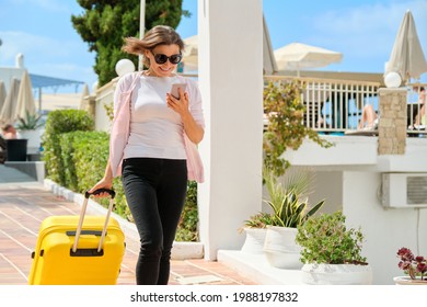 Tourism, travel, woman with suitcase walking along road of hotel complex - Powered by Shutterstock