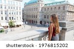 Tourism in Vienna, Austria. Back view of beautiful girl enjoying visiting the city of Vienna with famous historic palaces State Opera and Hotel Sacher.