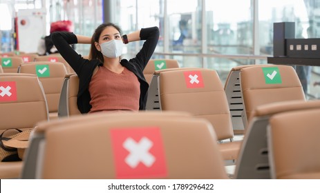 Tourist Asia woman wearing face mask or face shield sitting relax at the airport terminal before traveling during the Corona Virus pandemic, social distancing, new normal health awareness. worry free.
