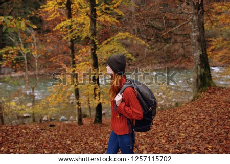 Tourist with a backpack and a hat with a jacket resting in the forest near the mountain river                           