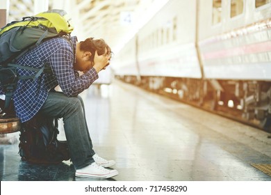 the tourist backpack man arrived late at the station. depressed and strain traveler sad sitting waiting at train station after mistakes a train makes wasting time in traveling.