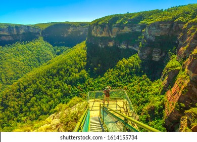 Tourist backpacker at balcony looks panoramic views at Pulpit Rock in Blue Mountains National Park, New South Wales, Australia. Australian landscape of Grose Valley, Blue Gum Forest and Govetts Leap.