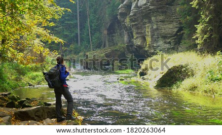 Tourist backpacker enjoy the view in the autumn forest by the river, Czech Switzerland, Bohemian Switzerland National Park Czechia 