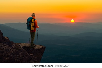 tourist - backpacker in touristic equipment stand on mountain peak and look beauty nature landscape with sunset or sunrise. travel and vacation concept